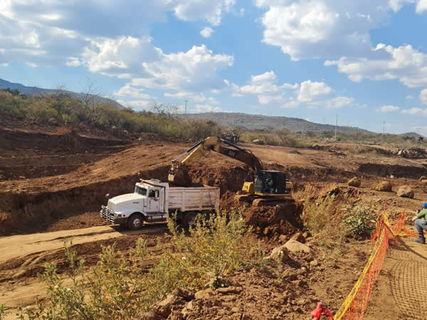 Muestra maquinaria cargando camiones de carga pesada.