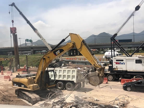 Muestra maquinaria demoliendo escombro para cargar.